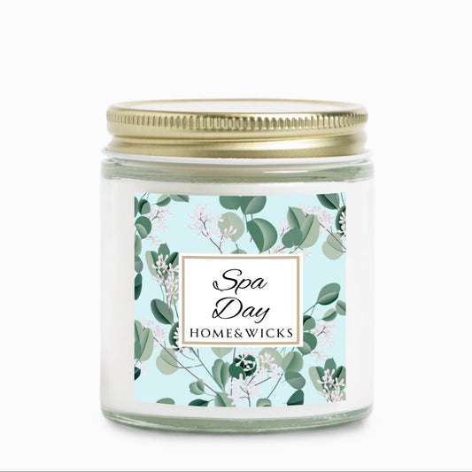 Spa Day candle by Homes & Wicks in a clear candle jar with gold lid with a eucalyptus floral label on a white background