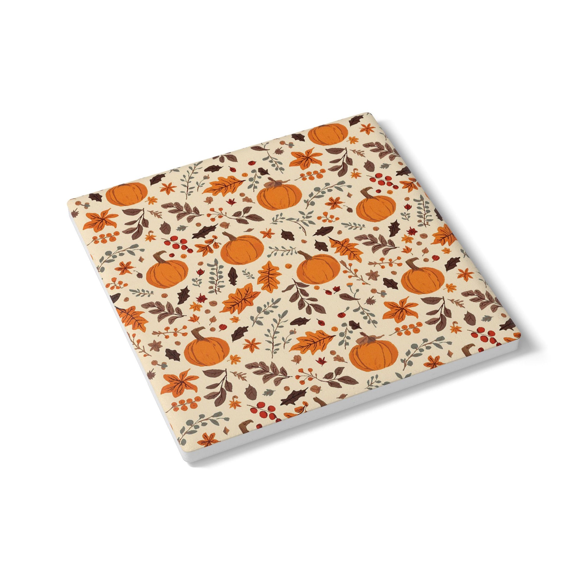 Square ceramic tile coaster with autumn-themed design featuring pumpkins and leaves on a beige background