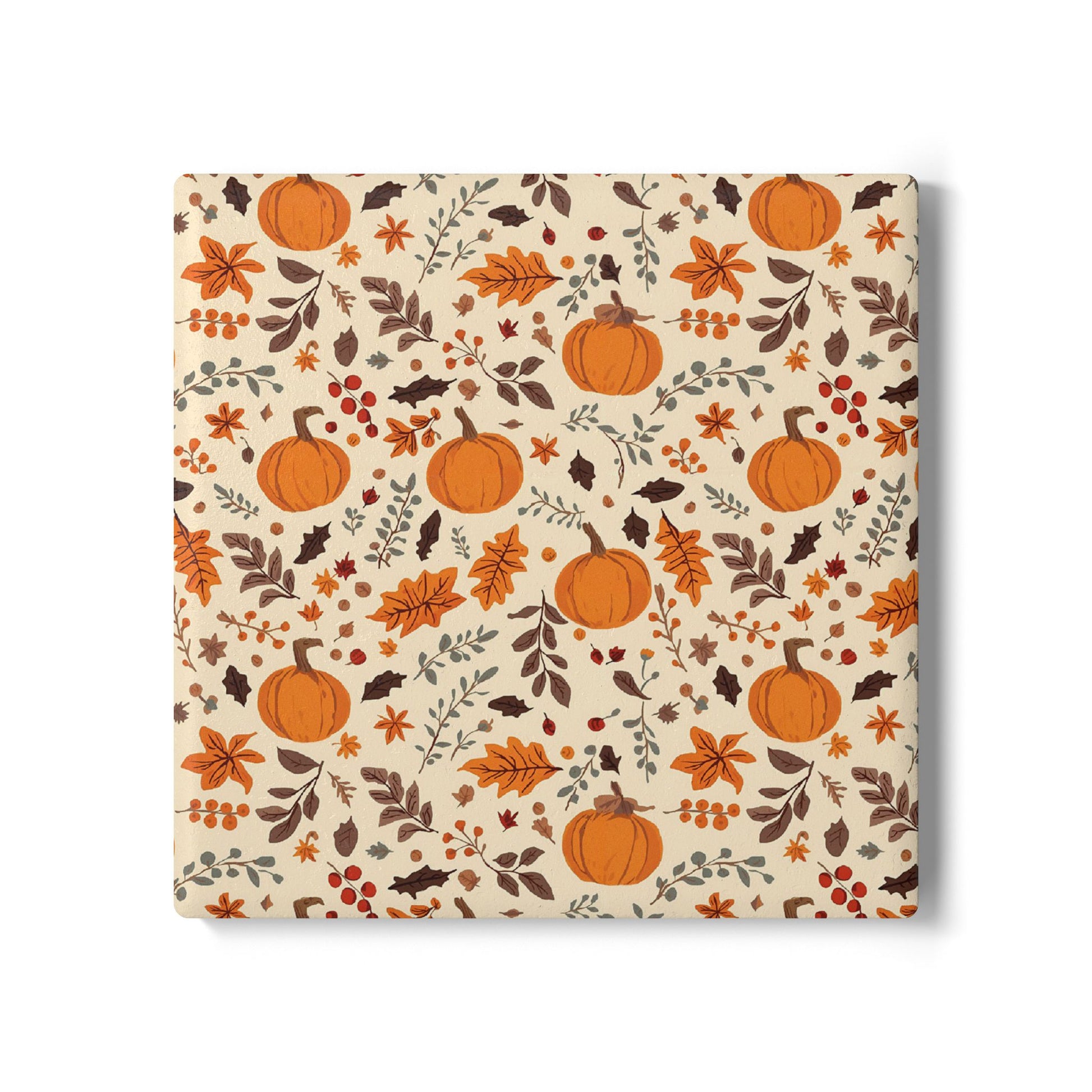 Square ceramic tile coaster with  autumnal design featuring pumpkins and leaves on a beige background