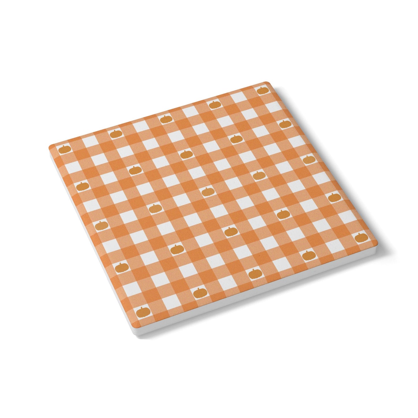 Square ceramic tile coaster with orange and white checkered gingham and pumpkin pattern on a white background