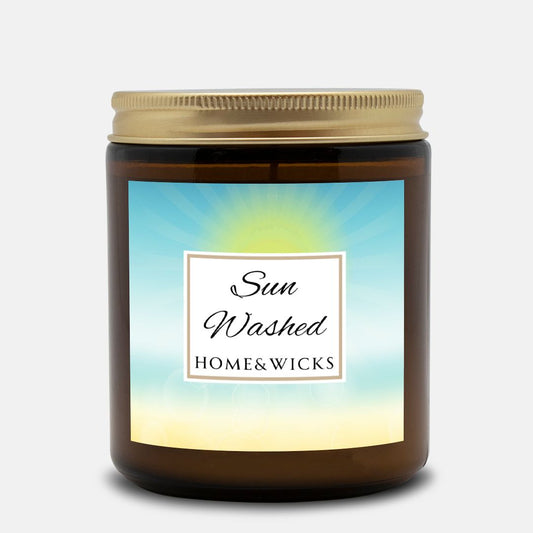 Candle in a 9 oz. amber jar with gold lid with 'Sun Washed' label on with sun graphic gradient background by Home & Wicks