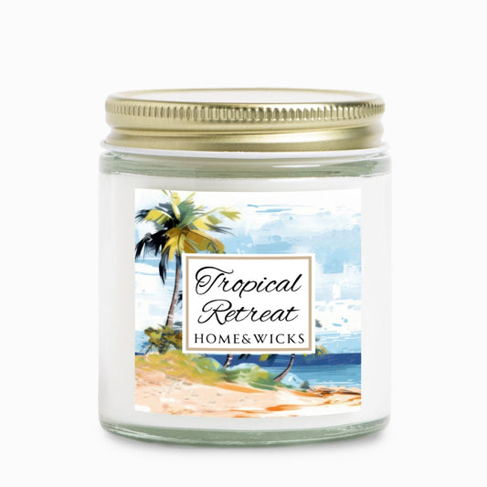 Homes & Wicks candle labeled 'Tropical Retreat' with a beach scene on a white background in a clear jar with gold lid