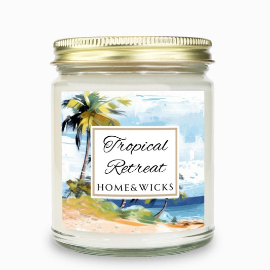 Tropical Retreat clear jar candle with gold lid labeled 'Tropical Retreat' with tropical beach seashore by Home & Wicks on a white background