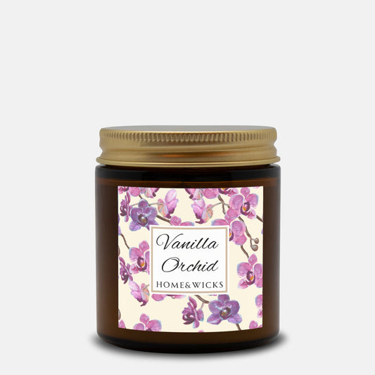Vanilla Orchid candle in a 4 oz. amber glass candle jar with gold lid with a pink and purple orchid floral label on a white background by Home & Wicks