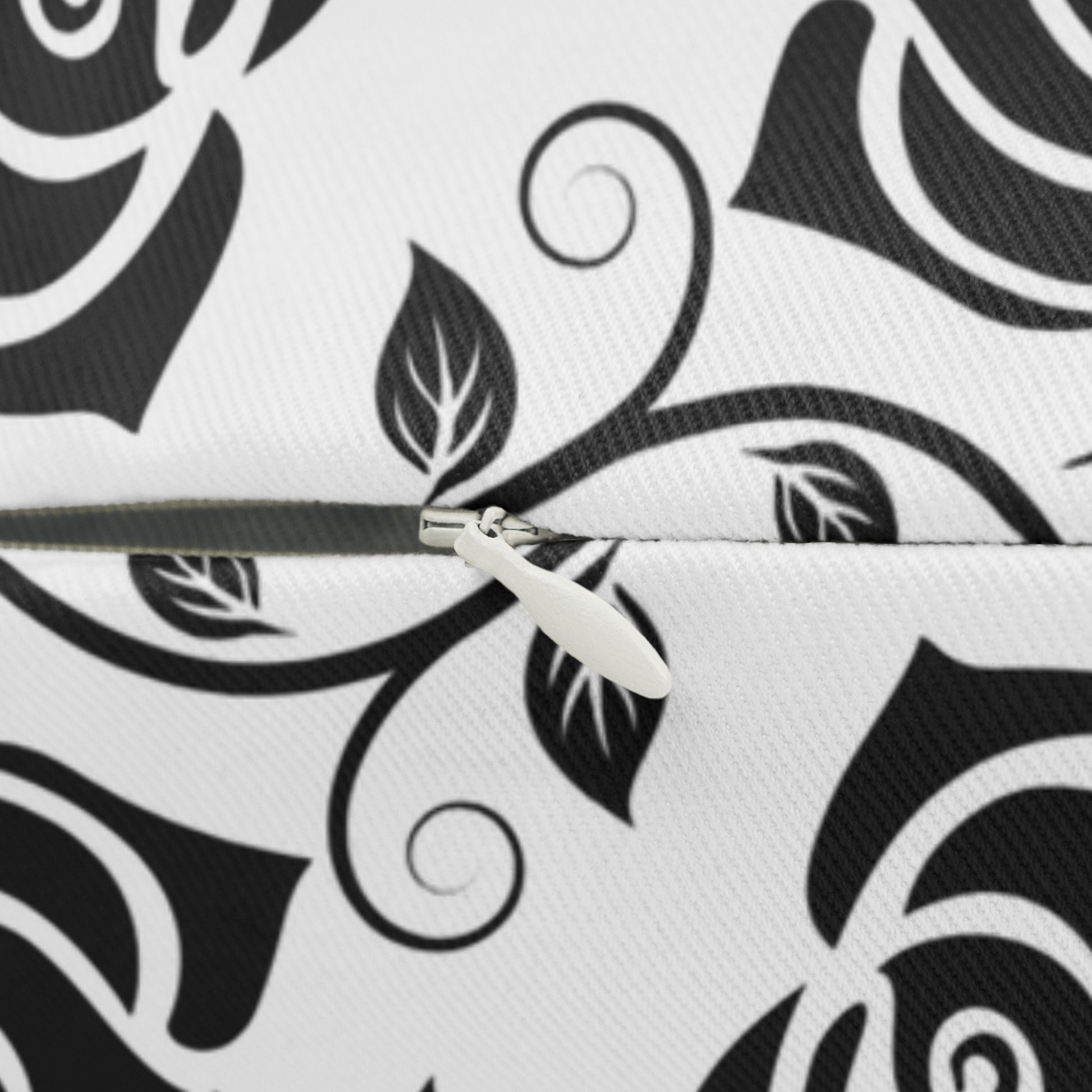 Close-up of zipper on a white decorative pillow with black roses pattern and zipper