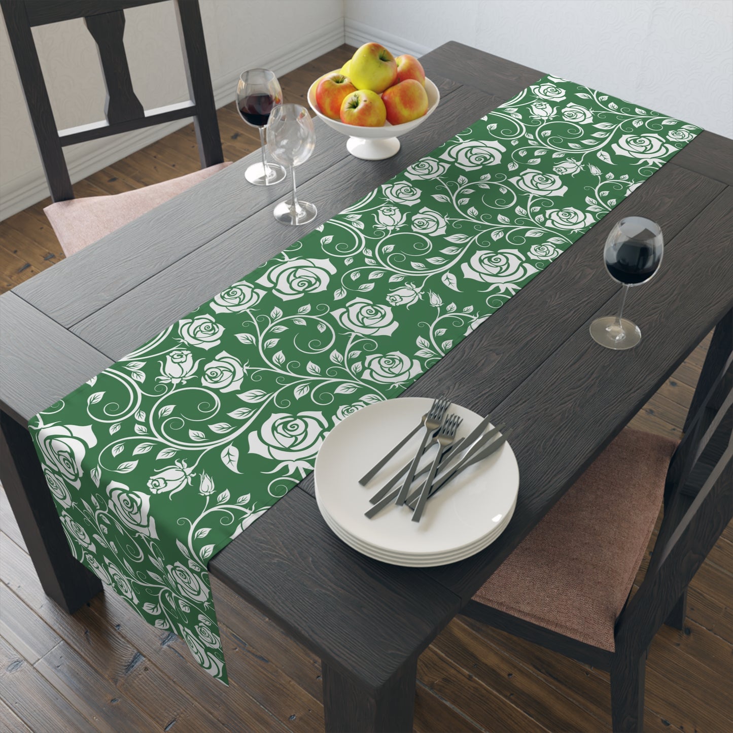 Green and white floral table runner on a wooden table with plates, cutlery, and fruit.