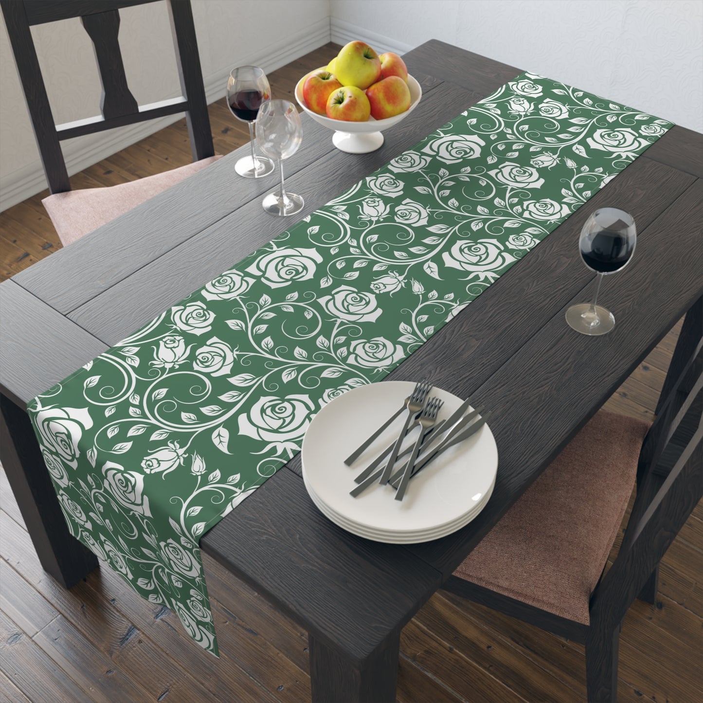 Green floral table runner on a wooden table with plates and cutlery.