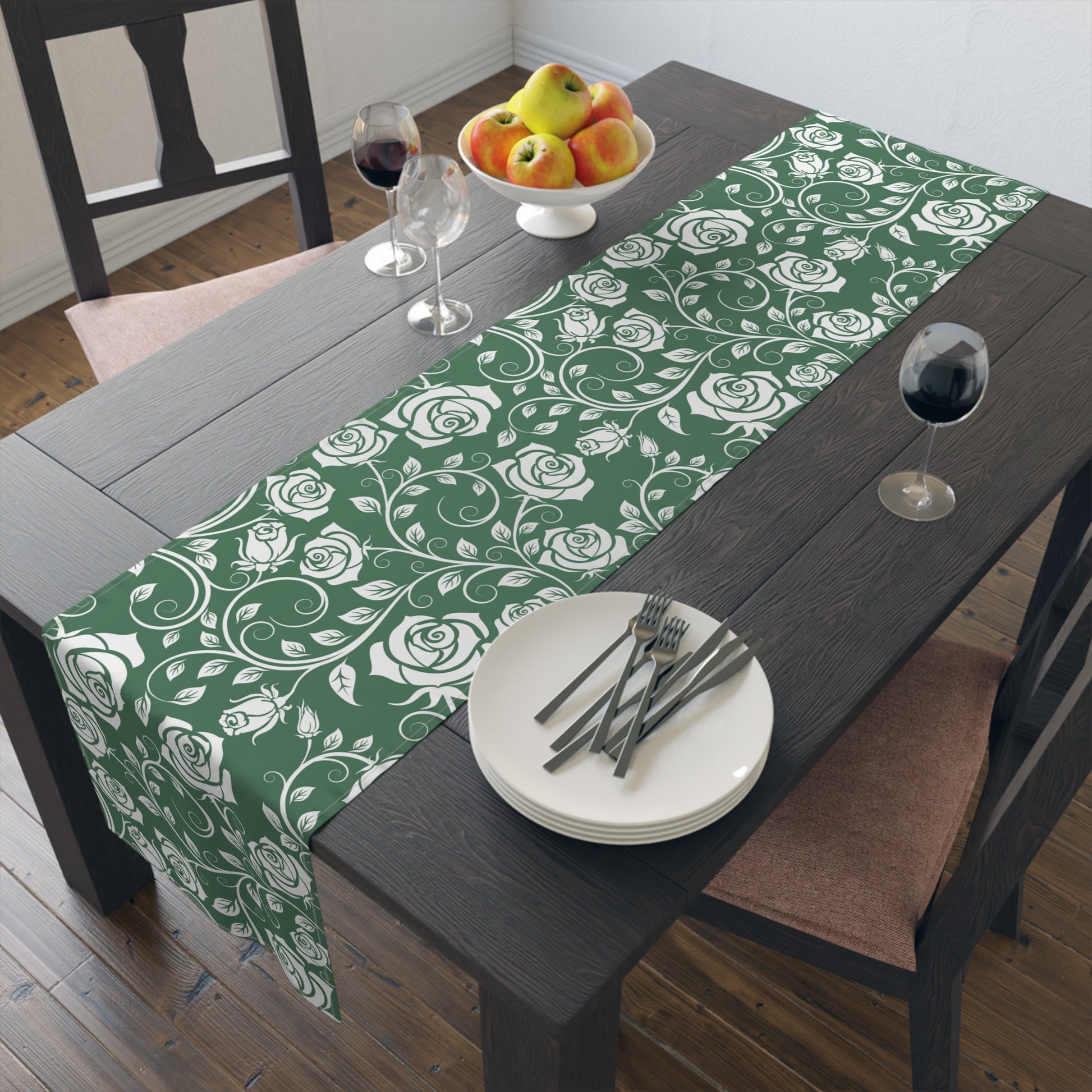 Green floral table runner on a wooden table with plates and cutlery.