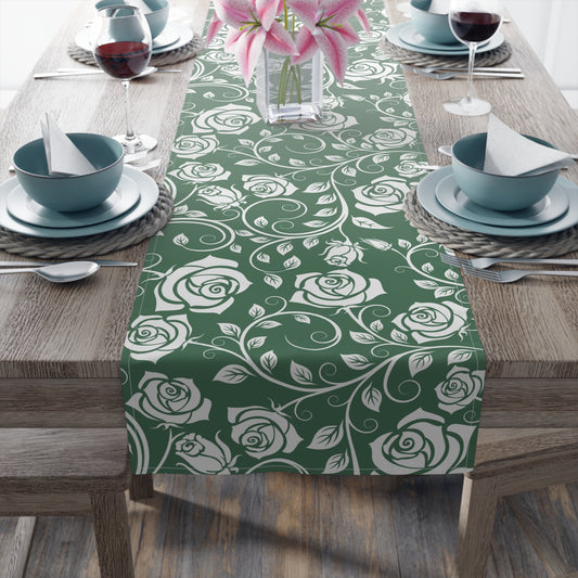 Table setting with a green and white floral table runner on a wooden table.