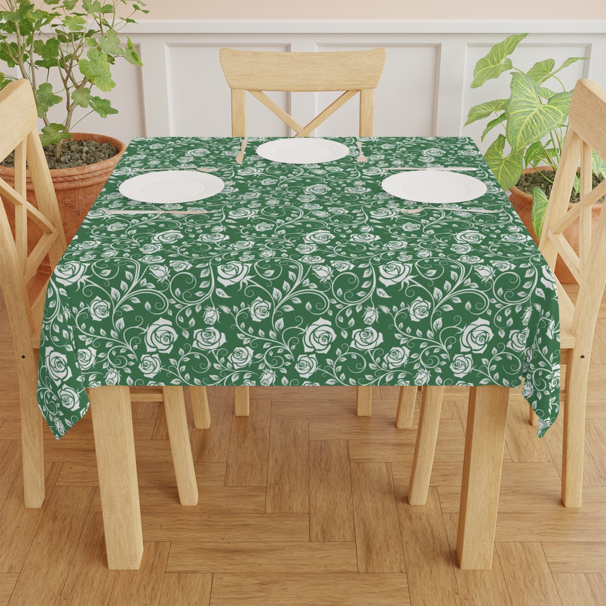 Dining table with a green and white  floral tablecloth on a wooden floor.