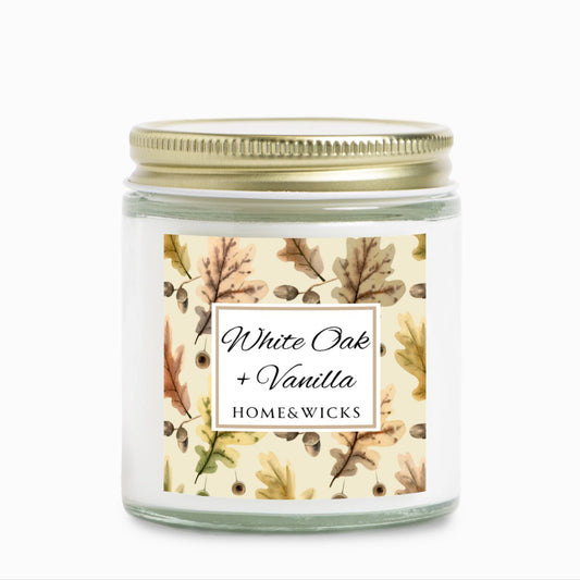 White Oak & Vanilla candle in a 4 oz. clear jar and gold lid with a decorative oak leaf design label featuring leaves and the brand 'Home & Wicks'.
