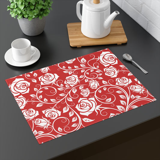 Red placemat with white rose pattern on a dark surface with tea set.