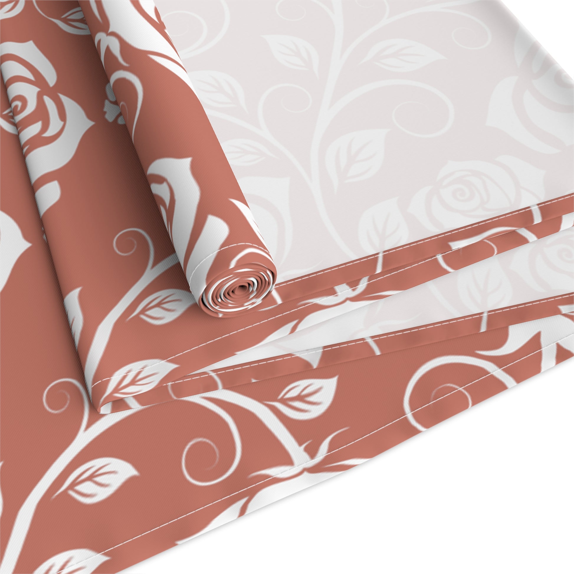 Red and White floral-patterned cotton table runner with white roses rolled up and folded on a white background