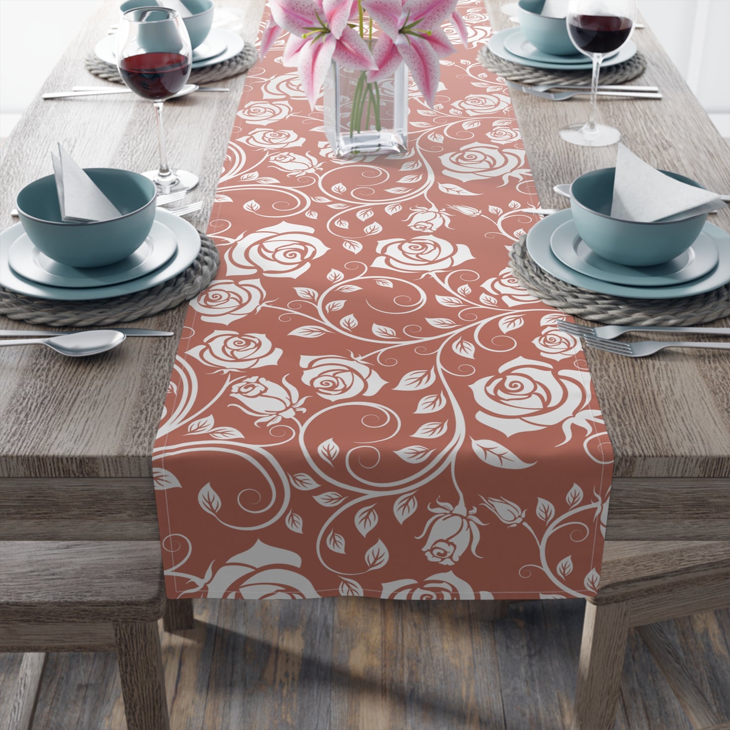 Table setting with a red and white floral patterned cotton table runner on a wooden table.