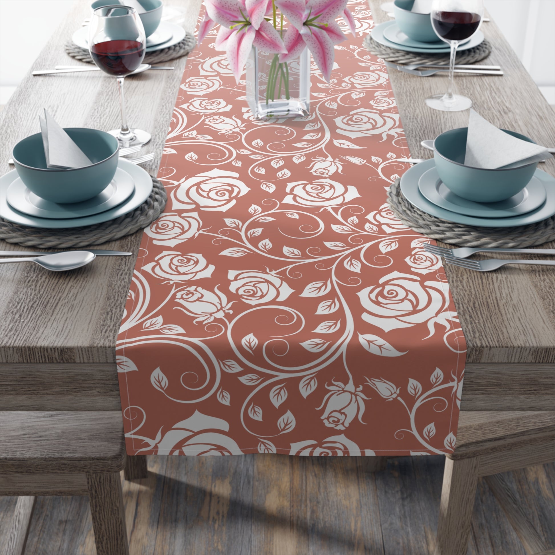Table setting with a red and white floral patterned cotton table runner on a wooden table.