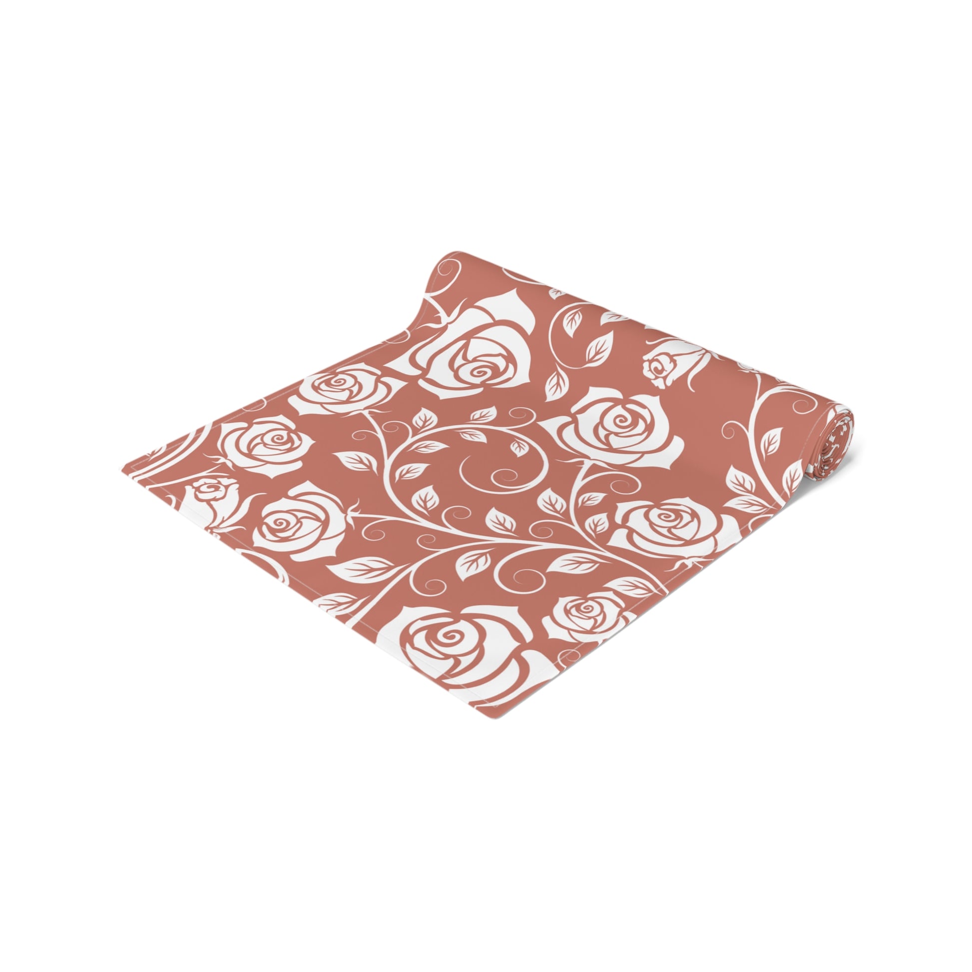 Floral patterned cotton table runner with red and white roses rolled up on a white background 
