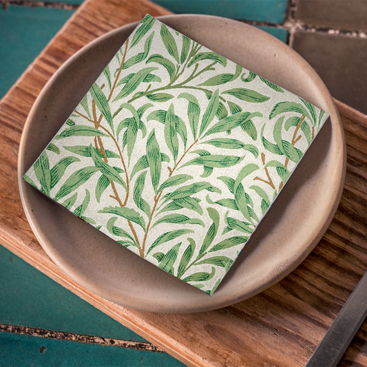 Willow Boughs 10 x 10 cocktail napkin with green leaf willow branch pattern on a brown plate on wood placemat