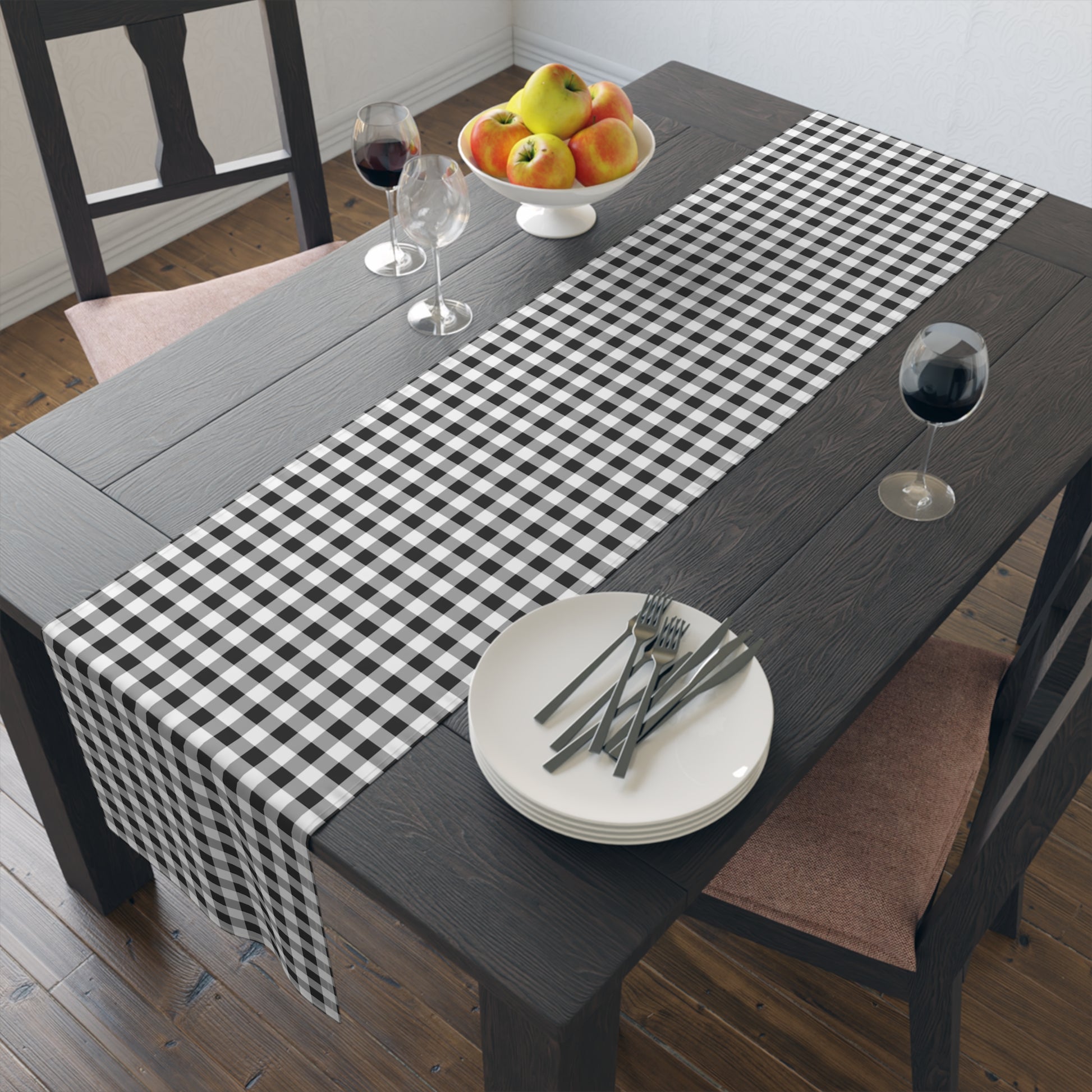 Table setting with a black and white checkered gingham table runner, plates, and cutlery on a wooden table.