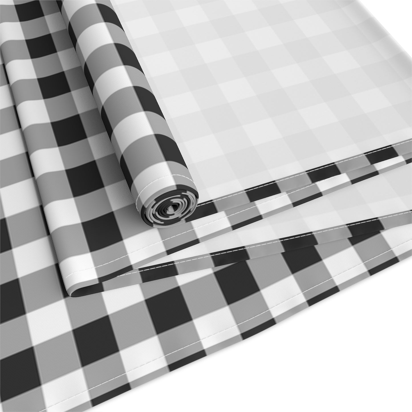 Rolled and folded black and white checkered gingham table runner on a white background