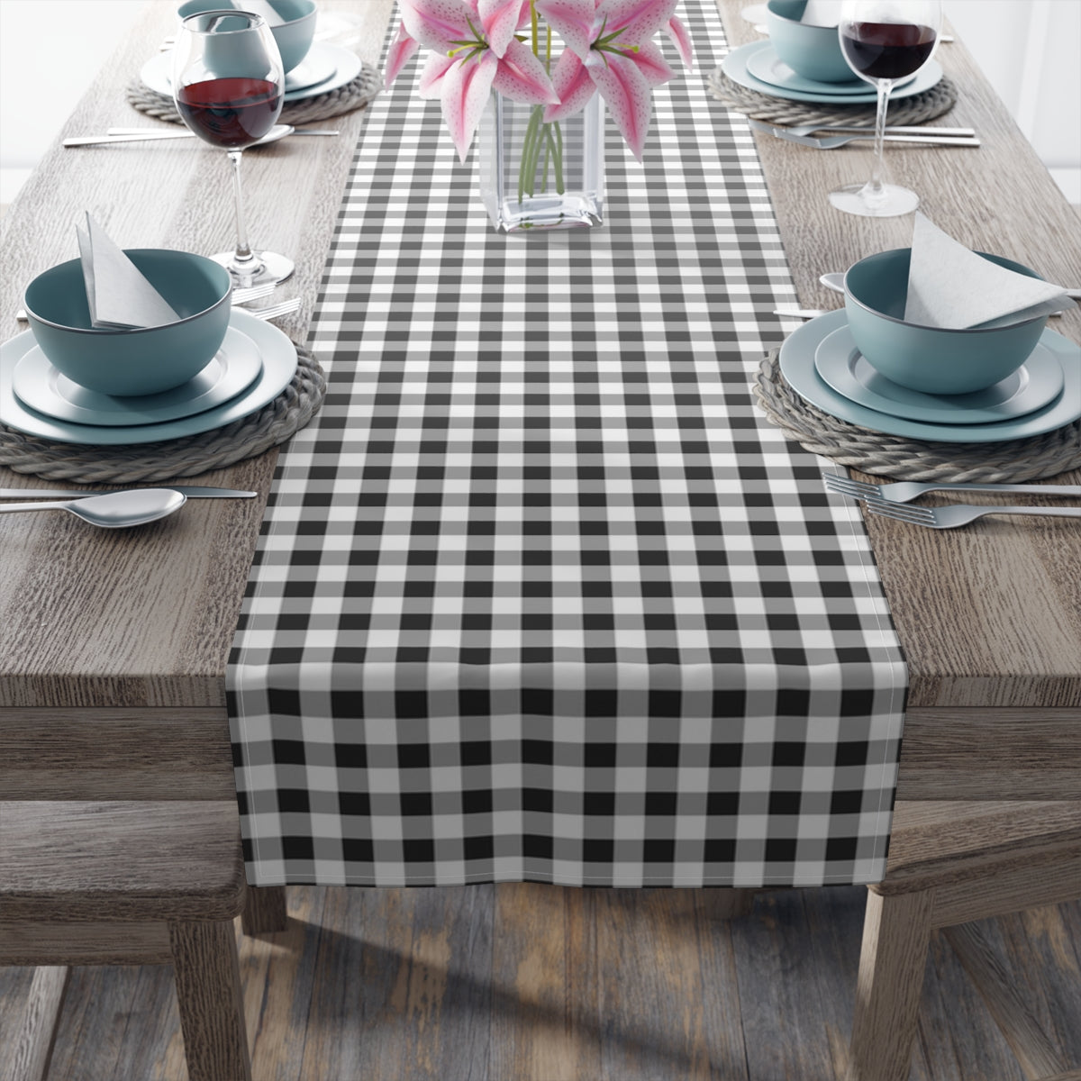 Table setting with a black and white checkered gingham table runner on a wooden table.